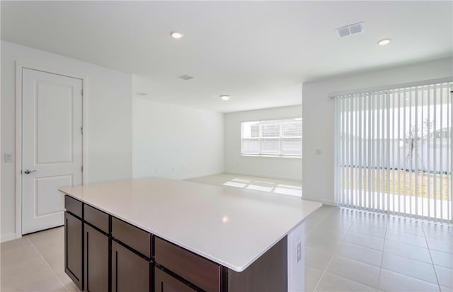 kitchen featuring a kitchen island, dark brown cabinets, and light tile patterned floors