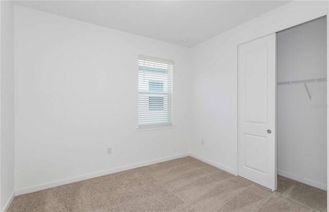 unfurnished bedroom featuring light colored carpet and a closet