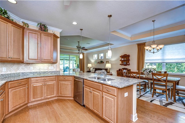 kitchen featuring pendant lighting, dishwasher, sink, kitchen peninsula, and a raised ceiling