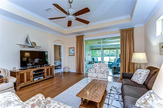 living room featuring a raised ceiling, ornamental molding, hardwood / wood-style flooring, and ceiling fan