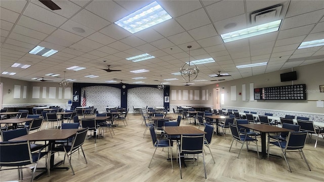 dining area featuring a drop ceiling, ceiling fan, and light parquet floors