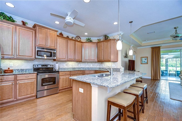 kitchen with sink, a breakfast bar area, decorative light fixtures, ceiling fan, and stainless steel appliances