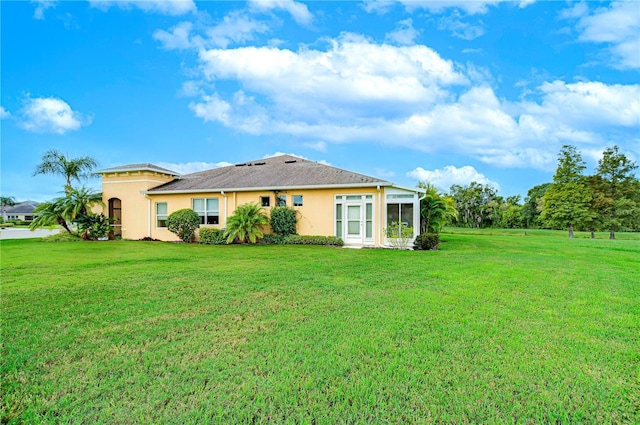 rear view of property featuring a yard and a sunroom