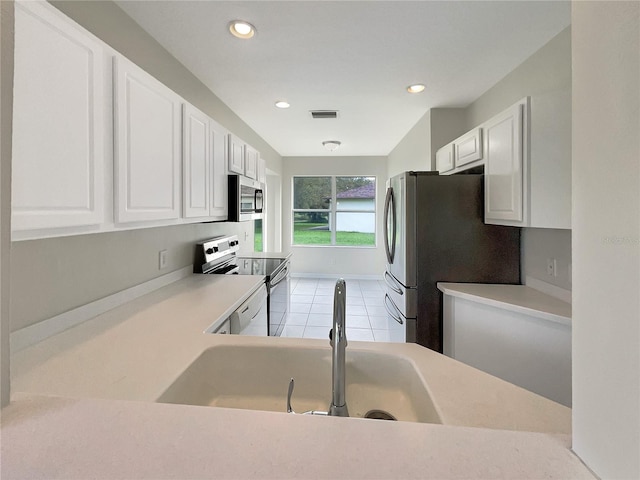 kitchen featuring white cabinetry, sink, light tile patterned floors, and stainless steel appliances