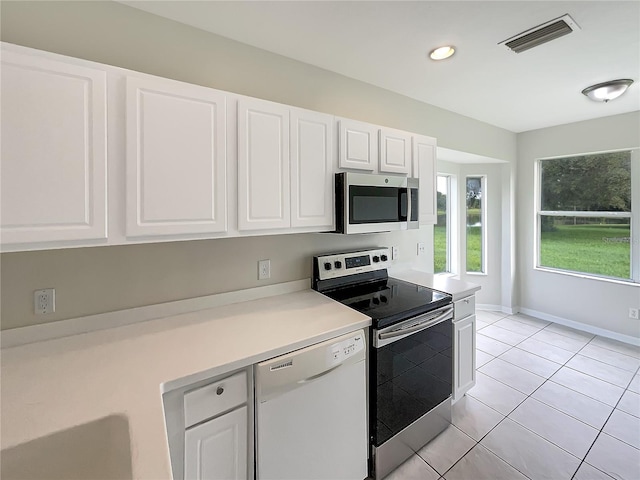 kitchen featuring appliances with stainless steel finishes, light tile patterned floors, and white cabinets