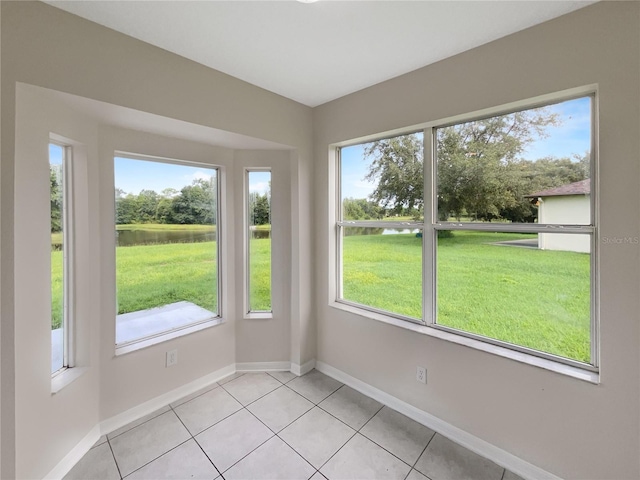 spare room featuring light tile patterned flooring and a water view