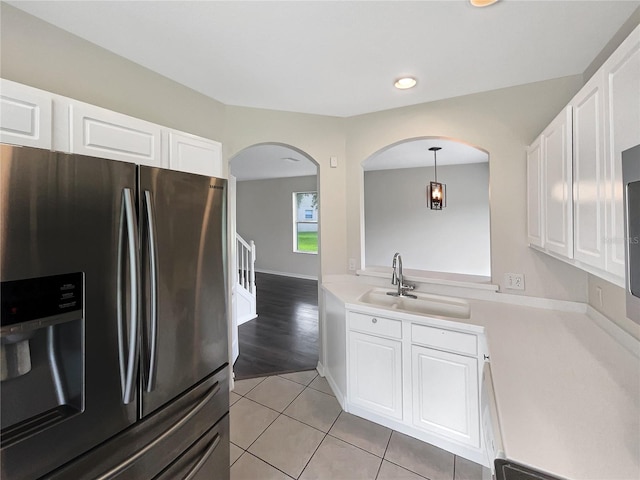 kitchen with pendant lighting, light wood-type flooring, sink, stainless steel refrigerator with ice dispenser, and white cabinetry