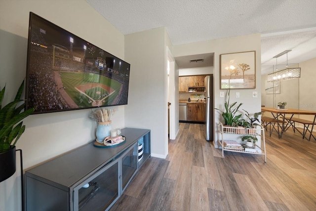 hallway featuring hardwood / wood-style flooring, a notable chandelier, and a textured ceiling