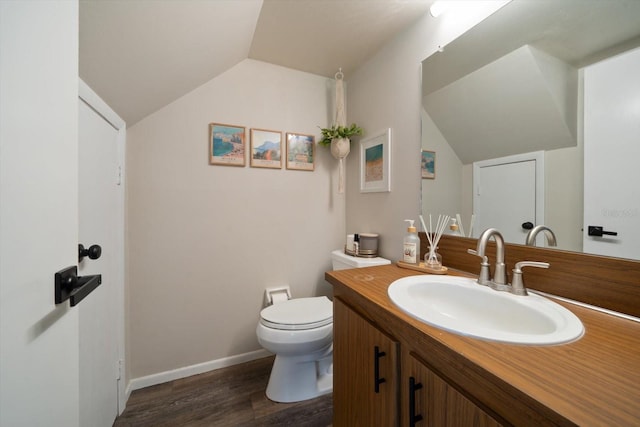 bathroom featuring wood-type flooring, lofted ceiling, vanity, and toilet