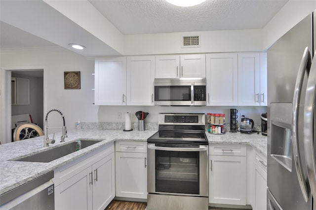 kitchen with visible vents, ornamental molding, a sink, appliances with stainless steel finishes, and white cabinetry