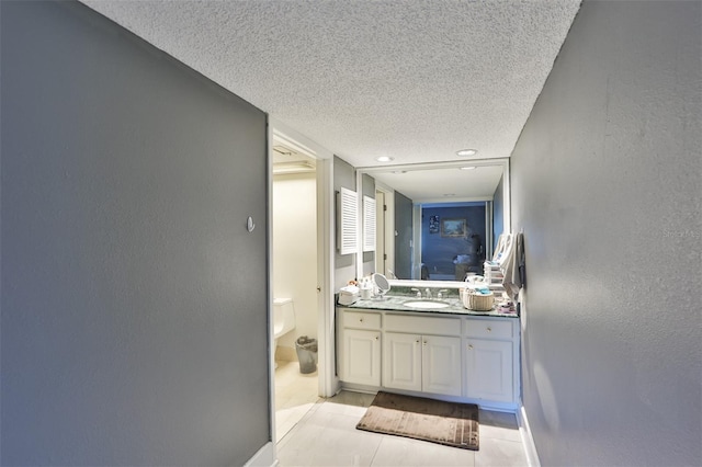 bathroom featuring a textured wall, baseboards, a textured ceiling, and vanity
