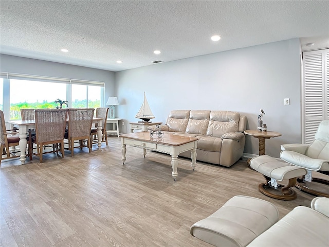 living area with visible vents, a textured ceiling, light wood finished floors, and recessed lighting