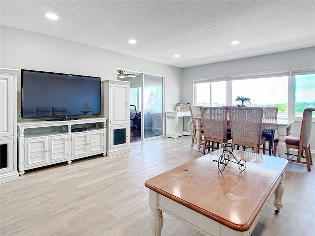 living area with light wood-type flooring, a ceiling fan, a textured ceiling, and recessed lighting