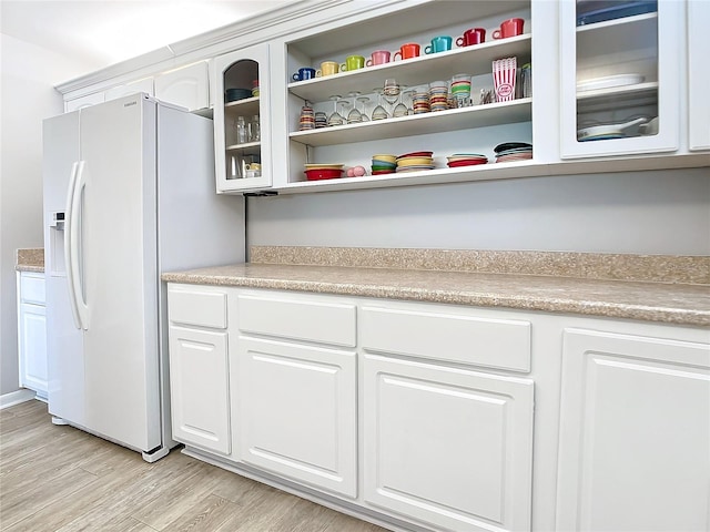 kitchen featuring light wood-type flooring, white fridge with ice dispenser, and white cabinetry