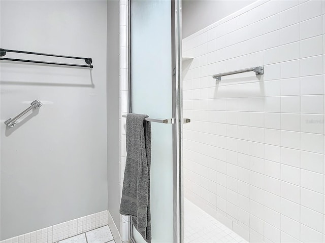 bathroom with a shower with door and tile patterned floors