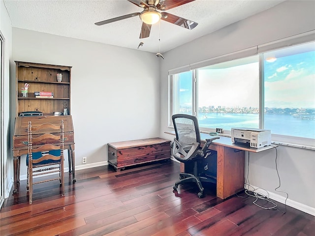 office with ceiling fan, a textured ceiling, dark hardwood / wood-style flooring, and a water view