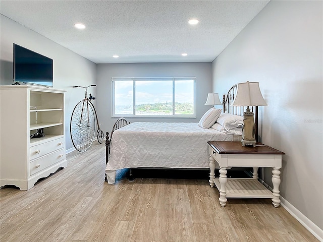 bedroom featuring baseboards, light wood-style floors, a textured ceiling, and recessed lighting