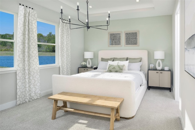 bedroom with a raised ceiling, an inviting chandelier, and light carpet