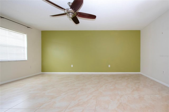 spare room with ceiling fan and light tile patterned floors