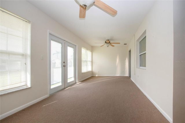 carpeted spare room featuring ceiling fan and french doors