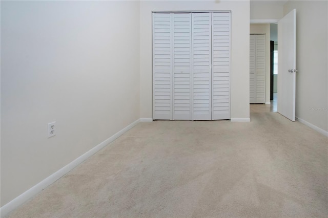 unfurnished bedroom with light colored carpet and a closet