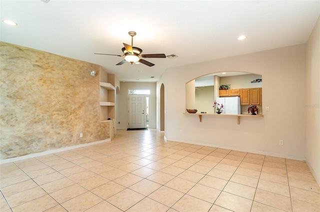 empty room with ceiling fan, built in features, and light tile patterned floors