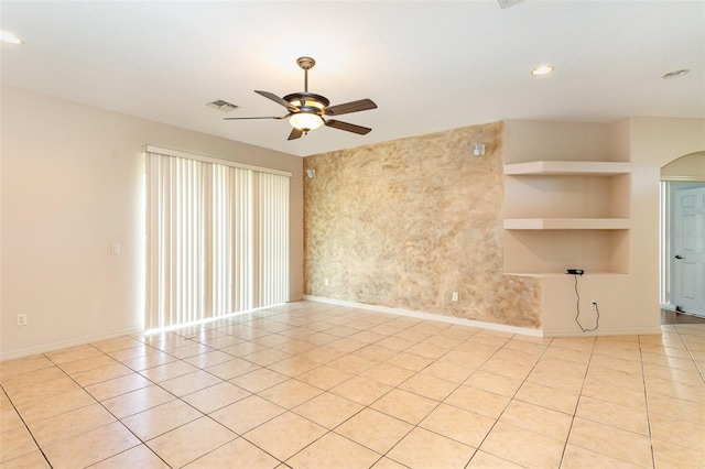 tiled spare room featuring ceiling fan and built in features