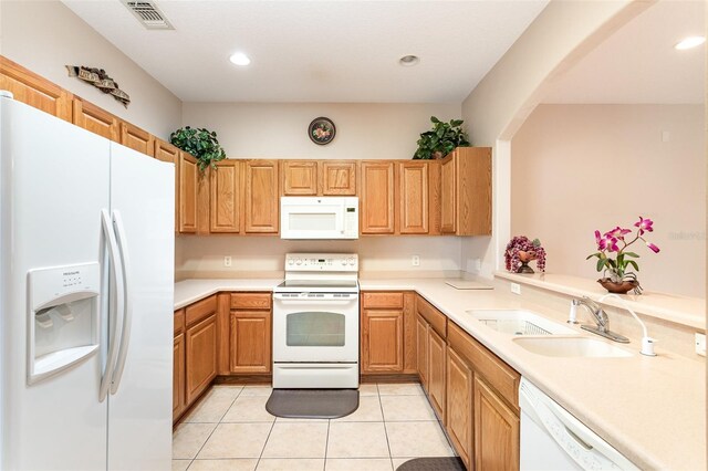 kitchen with light tile patterned floors, kitchen peninsula, sink, and white appliances