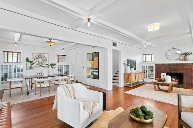 living room with a wealth of natural light, beam ceiling, hardwood / wood-style flooring, and a fireplace