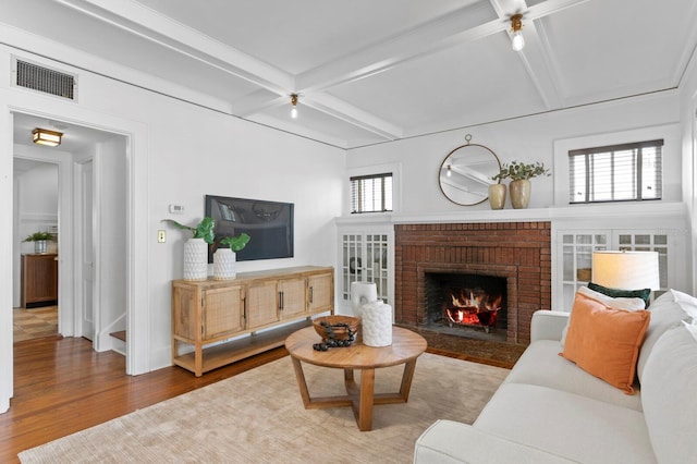 living room with beam ceiling, hardwood / wood-style floors, plenty of natural light, and a fireplace