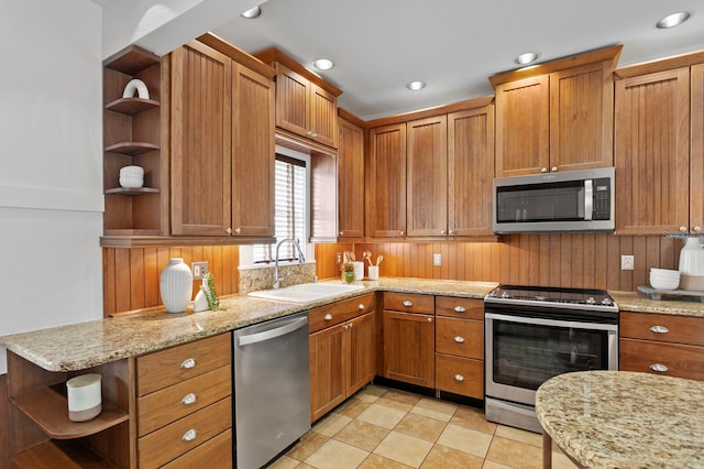 kitchen with stainless steel appliances, light stone counters, and sink