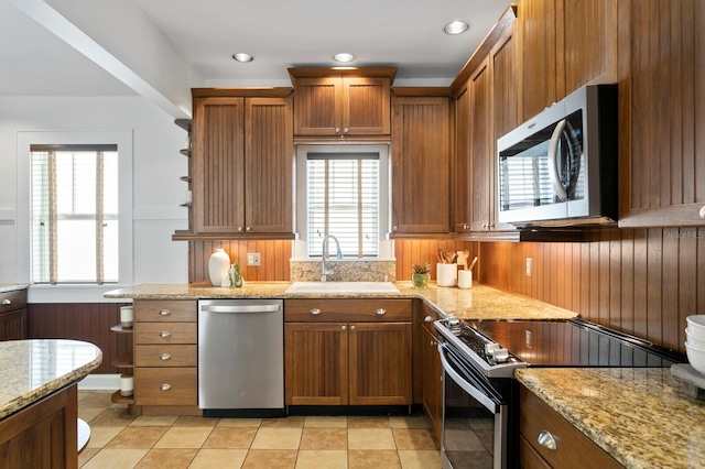 kitchen featuring stainless steel appliances, light stone counters, light tile patterned floors, and sink