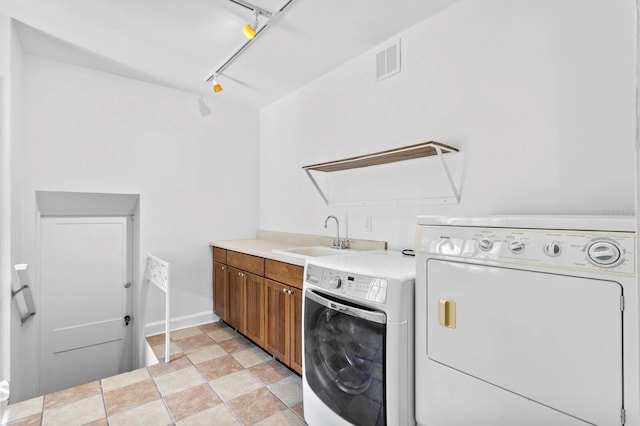 laundry room with cabinets, track lighting, washer and dryer, and sink