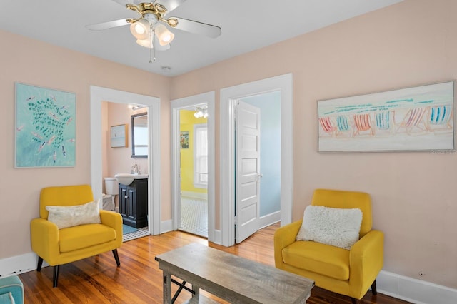 sitting room featuring ceiling fan, sink, and wood-type flooring