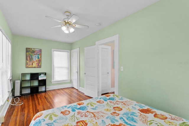 bedroom featuring ceiling fan, dark hardwood / wood-style floors, and multiple windows