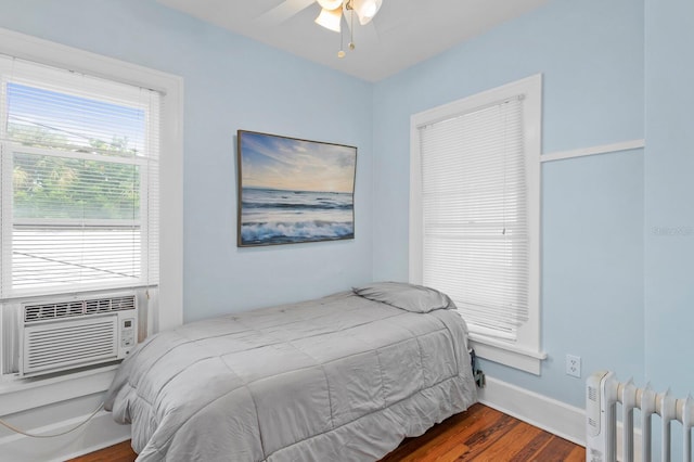 bedroom featuring cooling unit, ceiling fan, radiator heating unit, and dark wood-type flooring