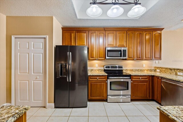 kitchen with stainless steel appliances, decorative light fixtures, and brown cabinets