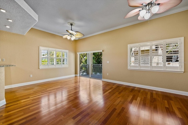 empty room with ornamental molding, baseboards, ceiling fan, and hardwood / wood-style floors