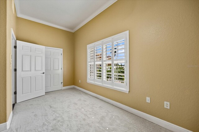 unfurnished bedroom with light carpet, a textured wall, ornamental molding, and baseboards