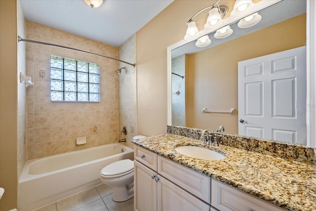 full bathroom featuring vanity, tiled shower / bath combo, tile patterned flooring, a textured ceiling, and toilet