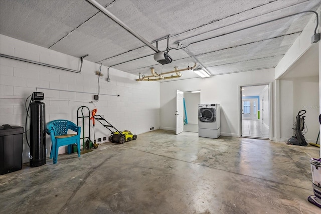 garage featuring washer / dryer, concrete block wall, and a garage door opener