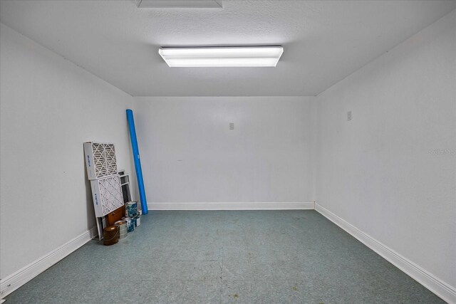 carpeted empty room with a textured ceiling and baseboards