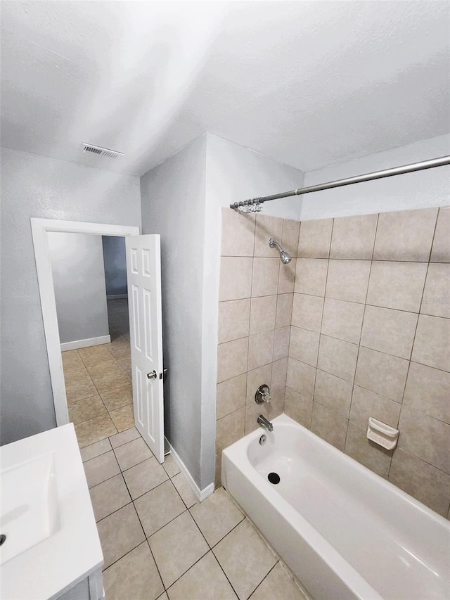 bathroom featuring tile patterned flooring, tiled shower / bath combo, and vanity