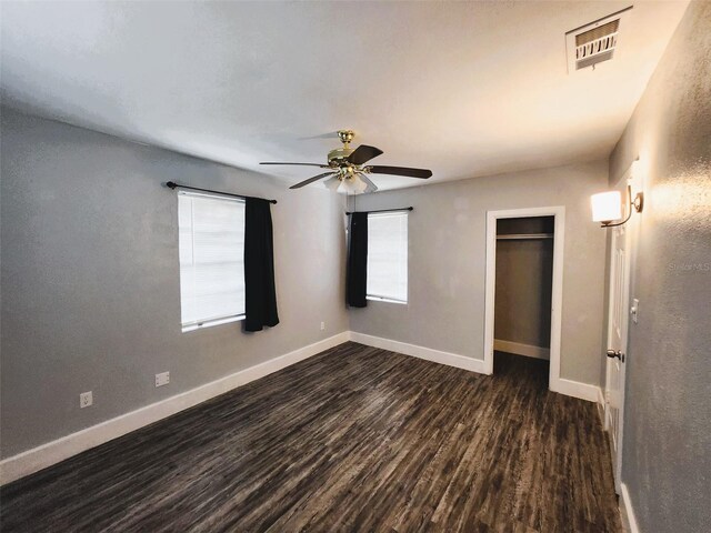 unfurnished bedroom featuring dark hardwood / wood-style floors, ceiling fan, and a closet