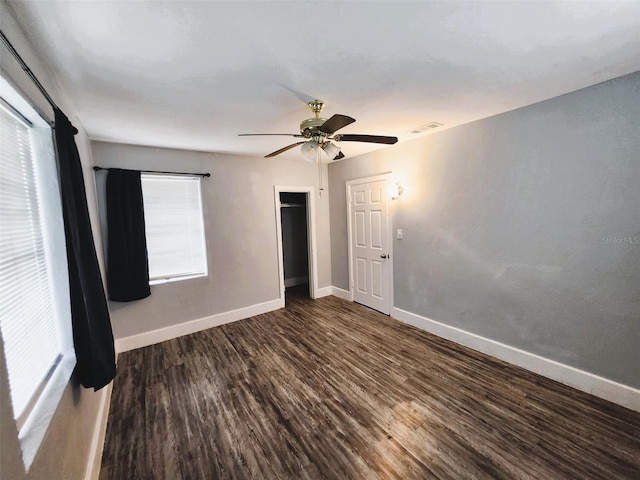 unfurnished bedroom featuring multiple windows, dark hardwood / wood-style floors, and ceiling fan