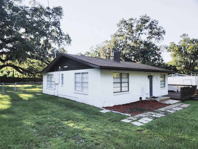 view of side of home with a deck and a yard