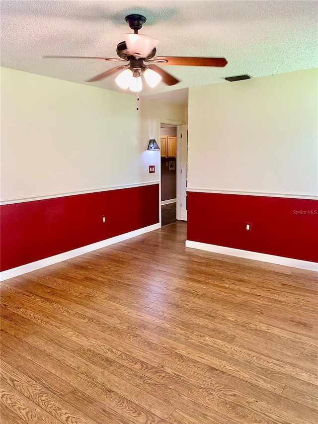 empty room with ceiling fan, a textured ceiling, and hardwood / wood-style floors