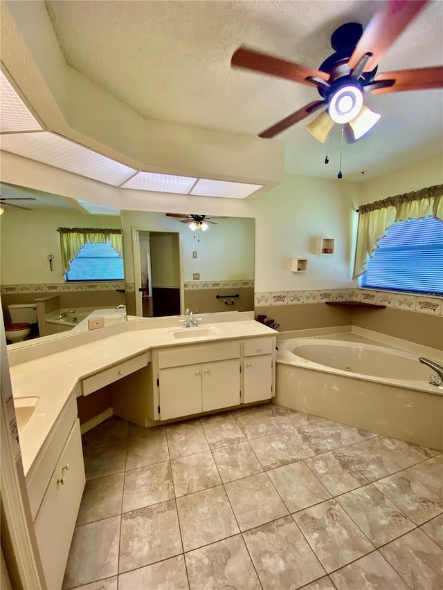 bathroom featuring a textured ceiling, ceiling fan, vanity, and a bathing tub