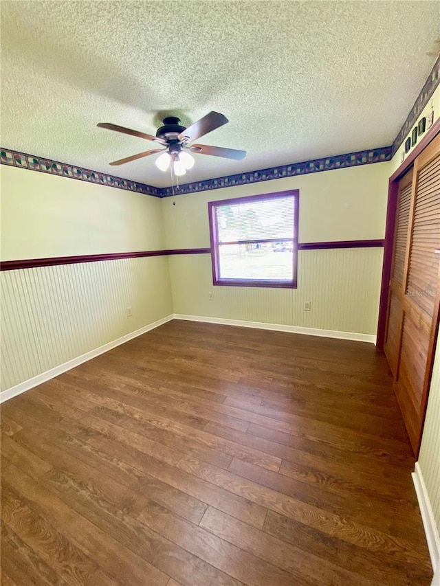 unfurnished bedroom featuring ceiling fan, a textured ceiling, a closet, and dark hardwood / wood-style floors