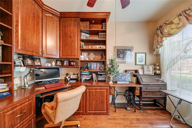 office space featuring built in desk, light hardwood / wood-style floors, and ceiling fan